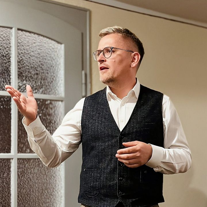 Andreas Lorenz steht in Aktion vermittelnder Pose im einem Raum und hält eine Rede
